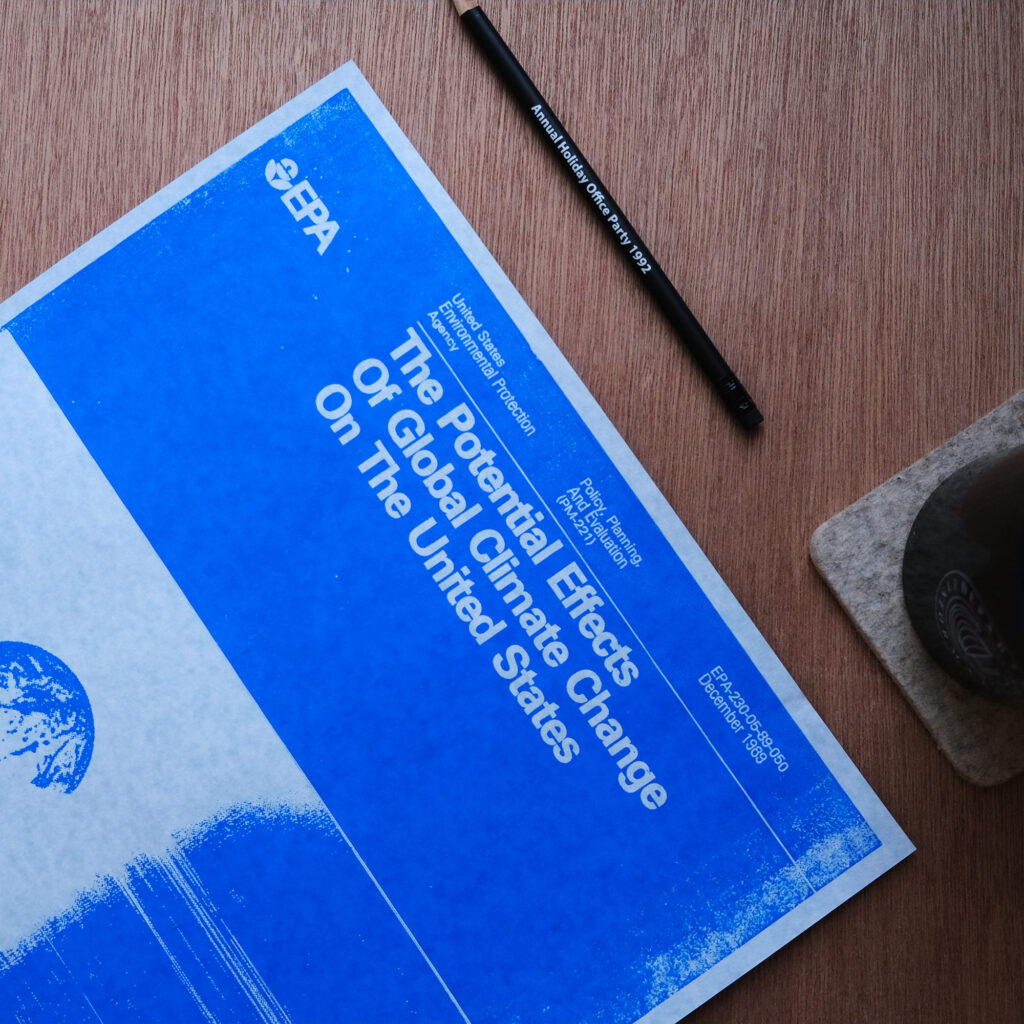 A photo of a framed vintage EPA poster from 1989 titled The Potential Effects of Global Climate Change on the United States, blue on blue paper, with a blue Earth