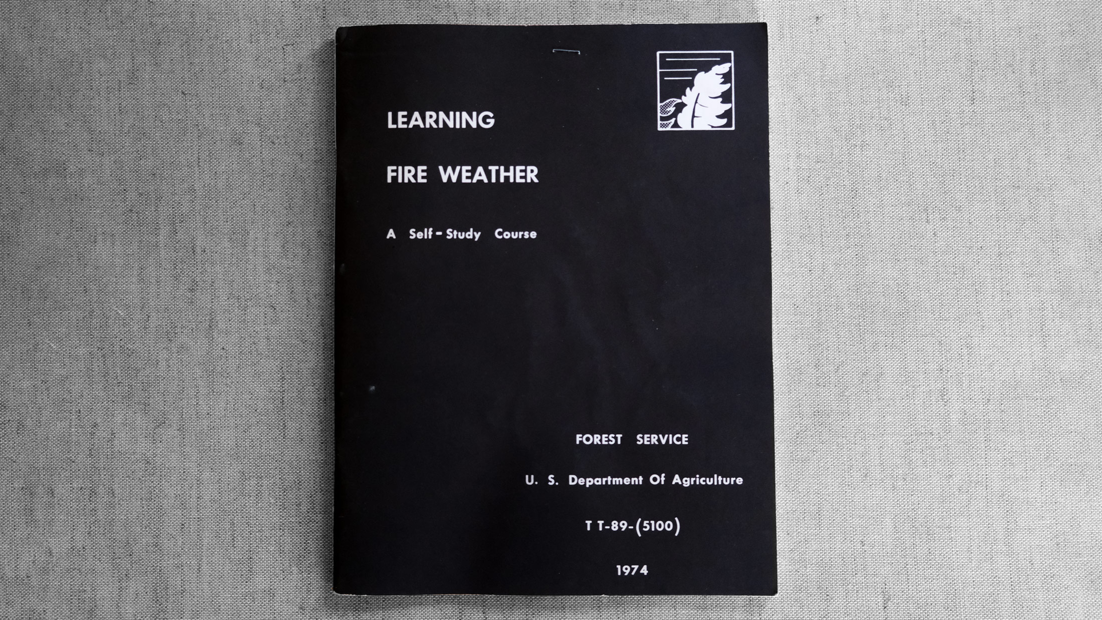 Learning Fire Weather: A Self-Study Course (1974) by the US Forest Service - Black blooklet, white text, on gray fabric